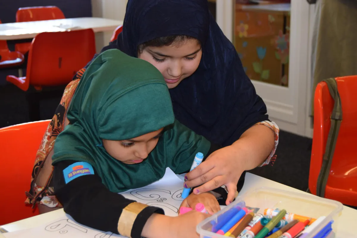 Two girls colouring a picture together with felt-tip pens